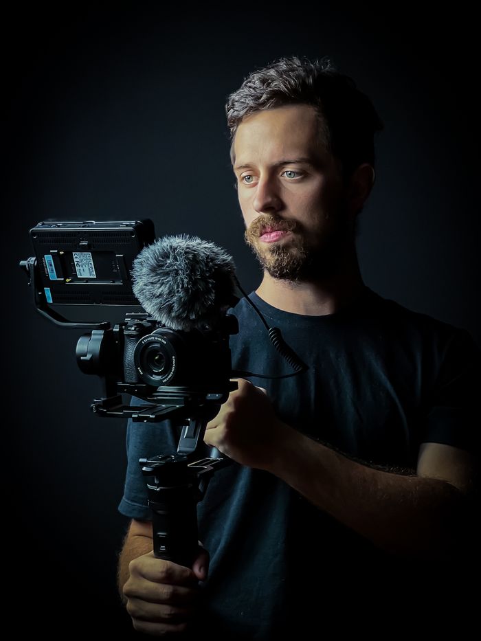 About A bearded videographer holding a camera rig during a studio photoshoot.